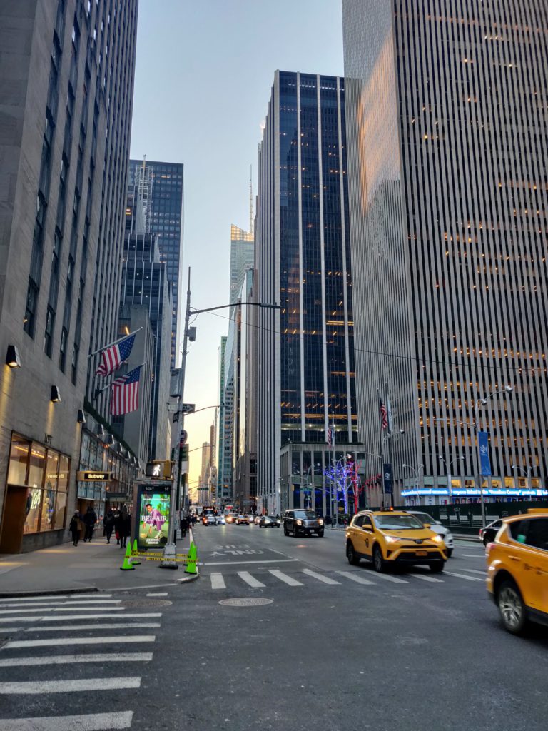 Rue de New York avec taxis jaunes, drapeaux américains et grands immeubles © Le Voyage de FloLili - Blog de Voyage