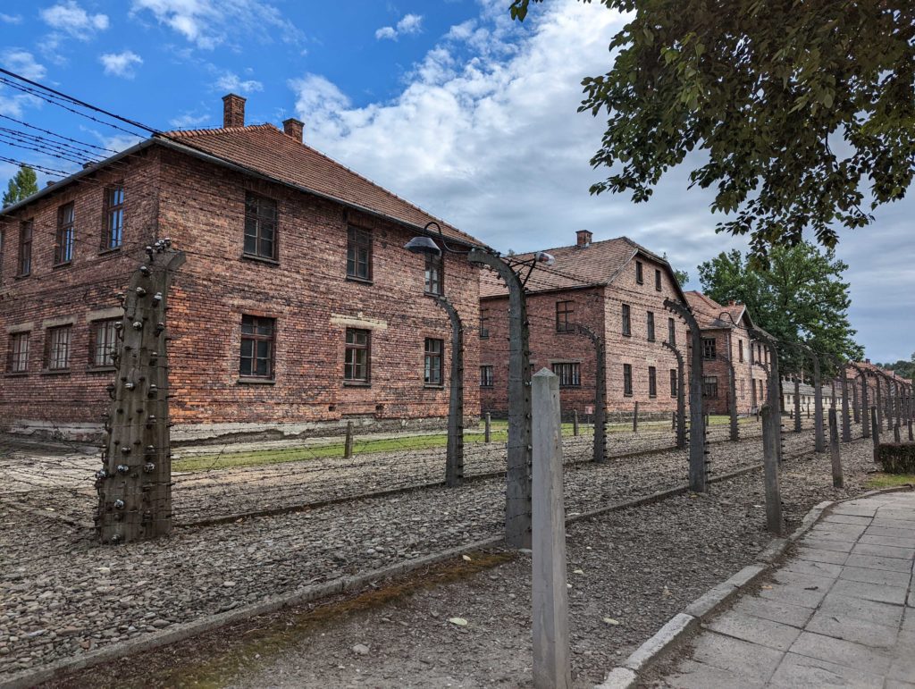 Bâtiments du camp d'Auschwitz en brique rouge avec barbelés devant © Le Voyage de FloLili - Blog de Voyage